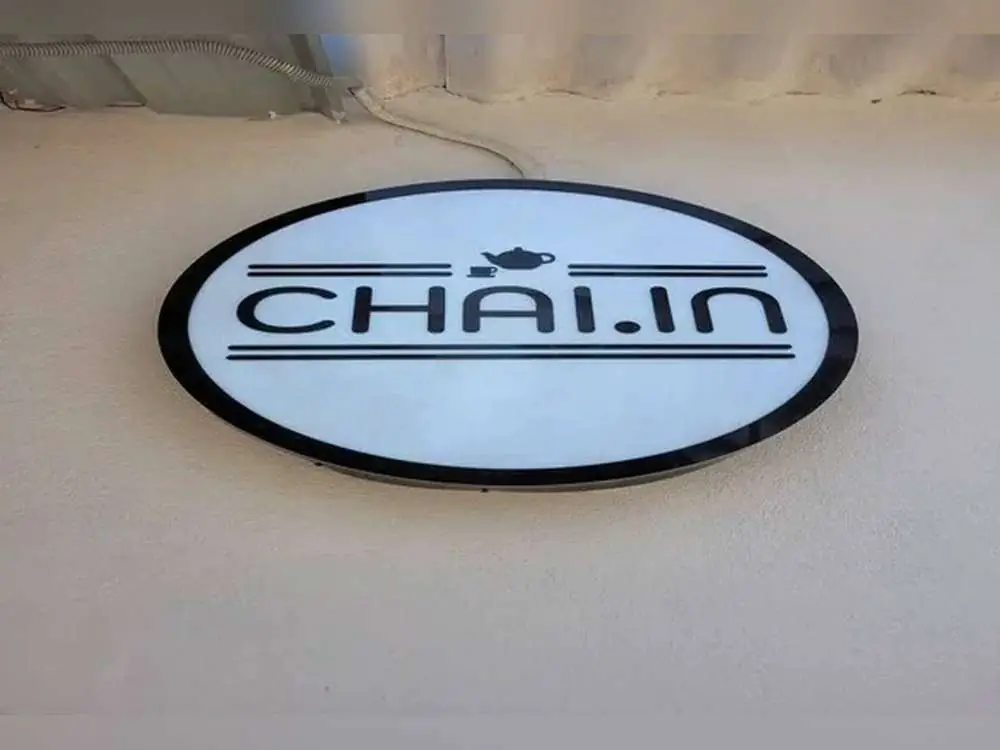Oval backlit lightbox sign board with the Chai.in logo mounted on an exterior wall